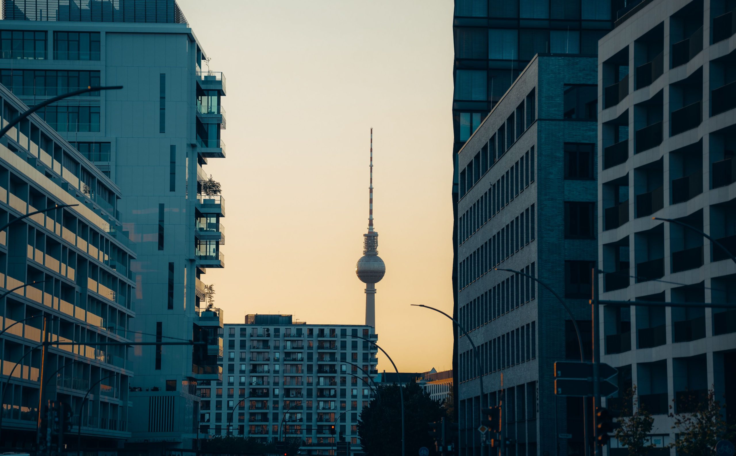 Berlin TV Tower visible between modern buildings at sunset, representing Germany's legal and urban context.