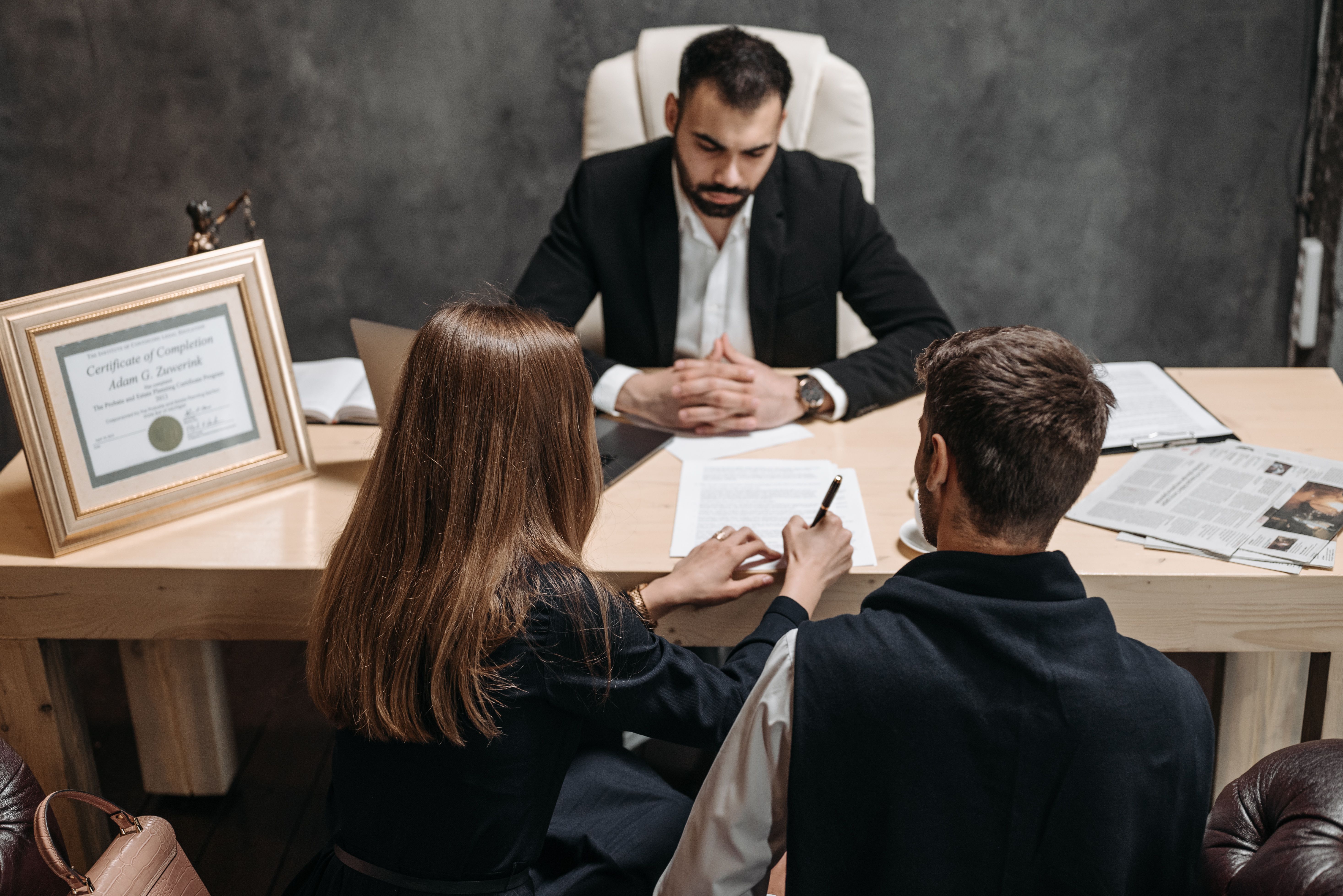 Lawyer discussing legal documents with clients in an office, illustrating advice about Germany's prostitution law.