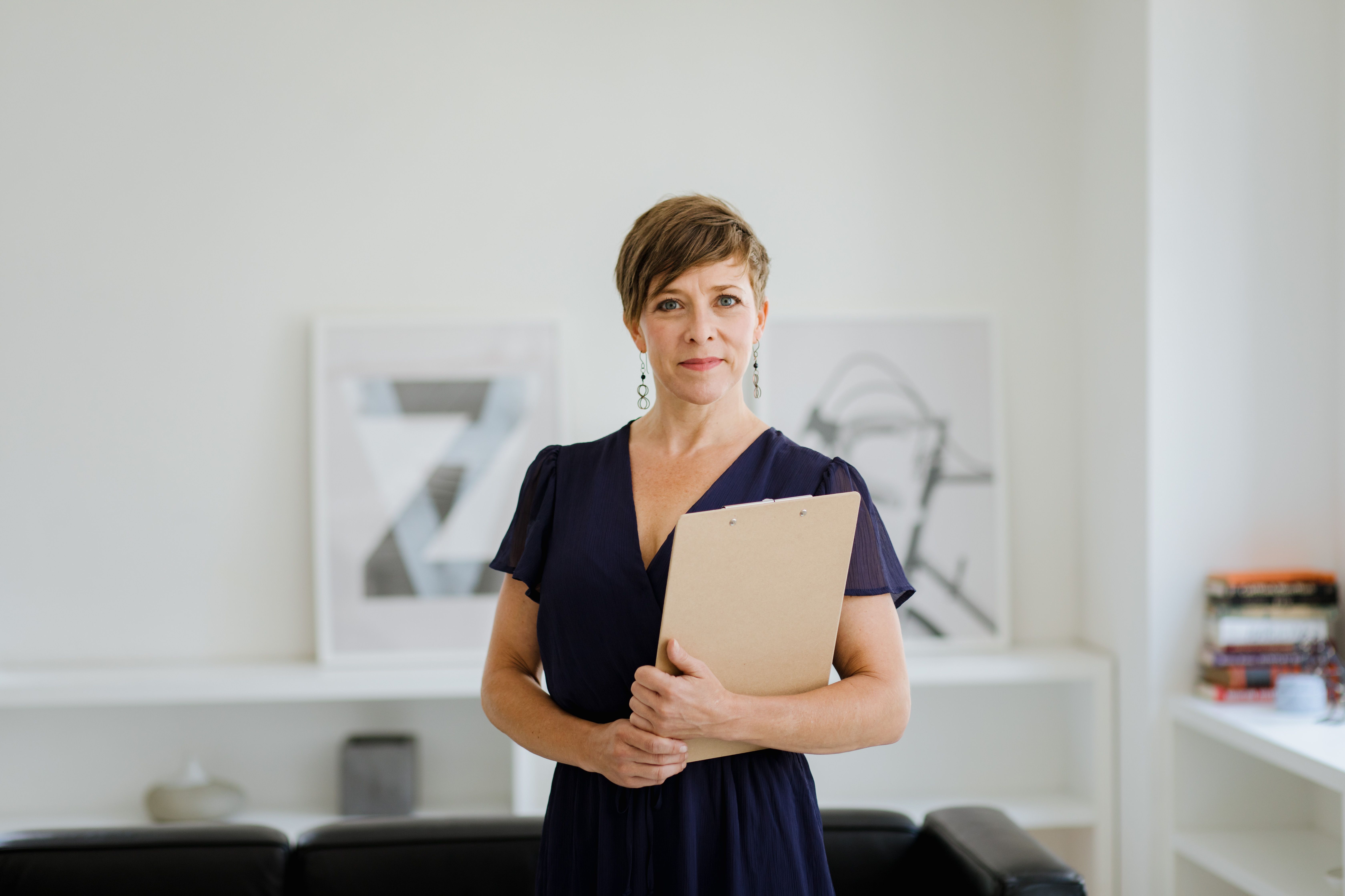 Confident professional woman holding a clipboard in an office, representing worker registration and rights.